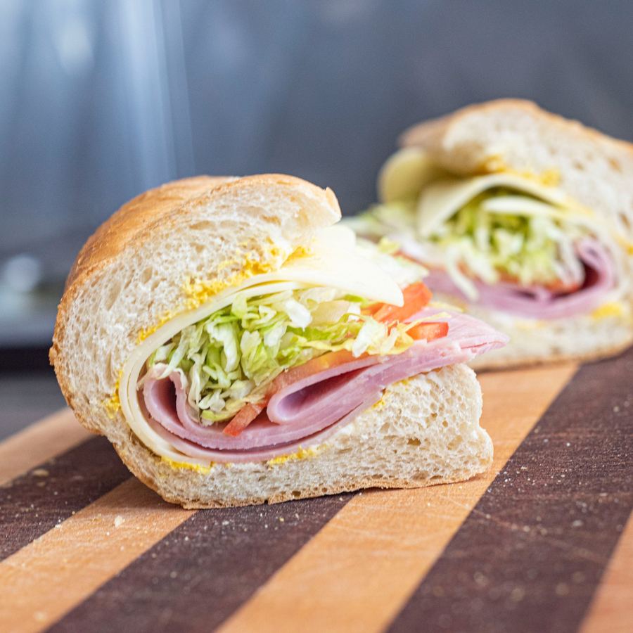 Classic ham and cheese sub open on a cutting board showing smoked ham and melted provolone on a fresh sub roll
